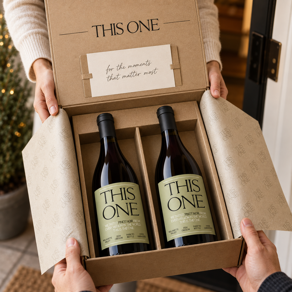Hands holding an open THIS ONE gift box with two bottles of Pinot Noir inside